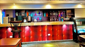 Eine Bar mit Sitzgelegenheiten, einer Theke und einer Flaschenauslage.