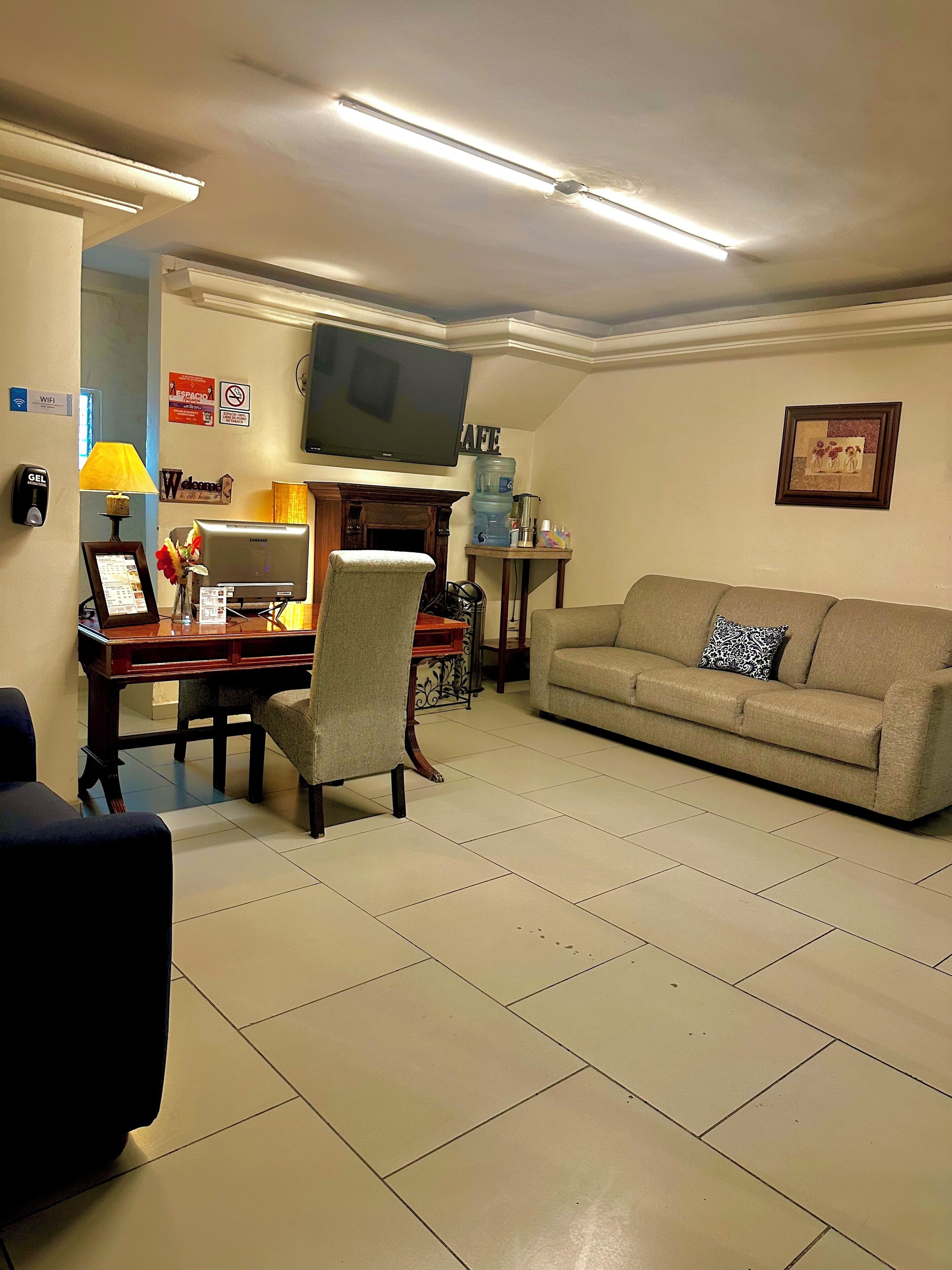A living room with a sofa, a TV, a fireplace, a desk with a computer, and a water dispenser.