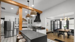 A modern kitchen with a central island, stainless steel appliances, and wooden beams. - Luxury Living on NW 23rd Ave, Walk Score 99 (Portland)