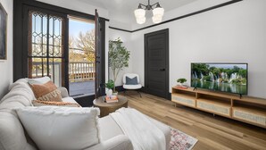 A modern living room with a sofa, a coffee table, a TV on a wooden stand, and a door. - Luxury Living on NW 23rd Ave, Walk Score 99 (Portland)