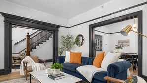 A living room with a blue sofa, a coffee table, and a staircase leading to another room. - Luxury Living on NW 23rd Ave, Walk Score 99 (Portland)