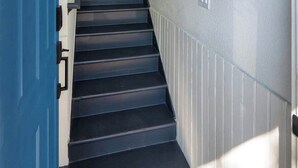 A staircase with a blue door on the left and a window on the right.