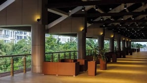 Un espacio interior amplio con ventanas grandes, columnas y plantas en macetas.