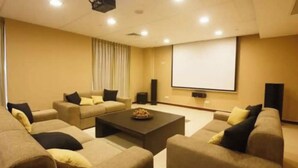 Una sala de cine en casa con sofás color crema, una mesa de centro y una pantalla grande.