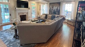 A spacious living room with a large sectional sofa, a fireplace, and a flat-screen TV mounted above it.