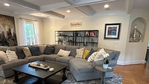 A modern living room with a sectional sofa, a coffee table, and a bookshelf.
