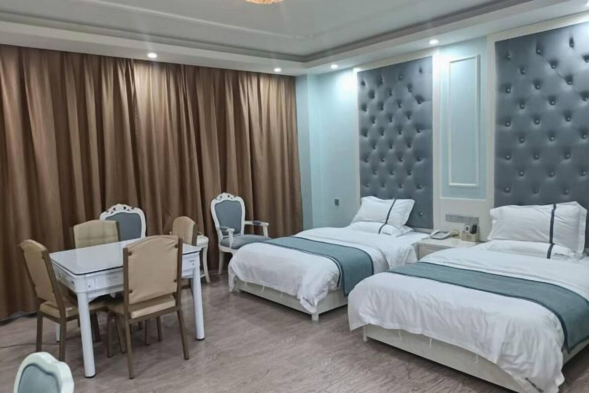 Hotellihuone, jossa on kaksi sänkyä, ruokapöytä ja tuoli.