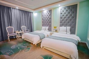 Une chambre d’hôtel avec deux lits, un coin salon comprenant une chaise et une table, et un grand miroir.