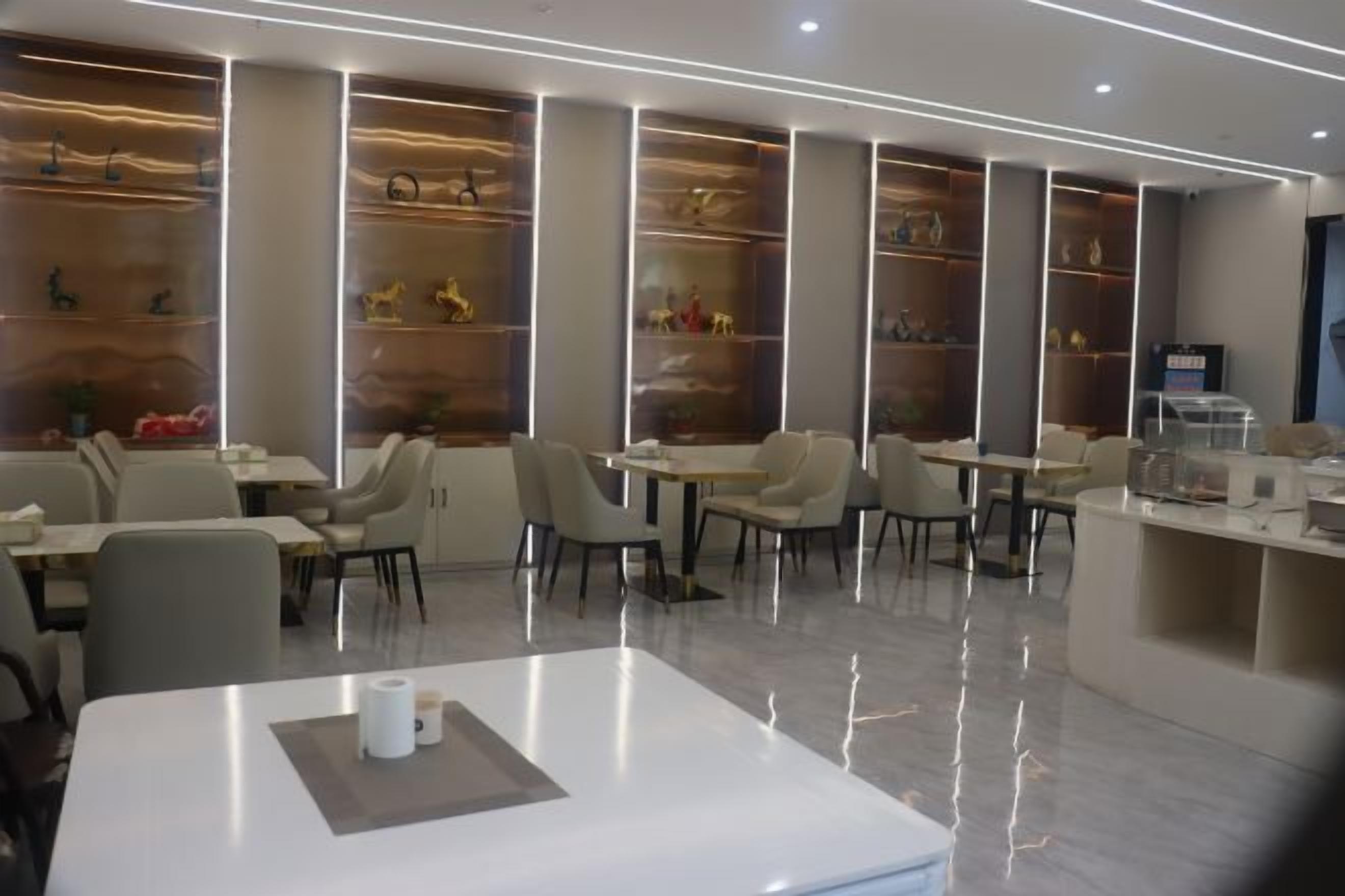 A modern restaurant with a clean, minimalist design, featuring white tables, comfortable seating, and decorative shelves with items.