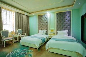 Une chambre d’hôtel avec deux lits, un coin salon avec des fauteuils, une petite table et un tapis décoratif.