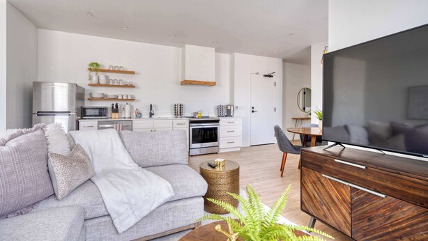 A modern living room with a grey sofa, a wooden coffee table, and a flat-screen TV. - Alberta Arts - 2BR - Walk to Food, Shops, & Art (Portland)