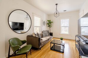 Un salon avec un canapé, un fauteuil vert, une table basse et un téléviseur.