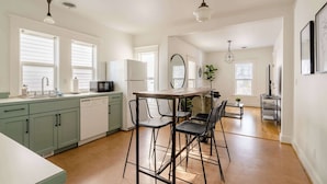 Una cocina moderna con comedor, que cuenta con una isla central, taburetes de bar e iluminación colgante.