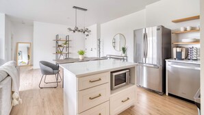 A modern kitchen with a central island, stainless steel appliances, and a minimalist design. - Sleeps 12 - Exclusive Floor - Great for Groups (Portland)