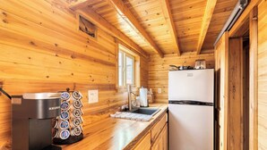 A wooden cabin kitchen with a coffee maker, sink, and refrigerator. - The Timber Nook • Rustic Charm • Walkable Location (Portland)