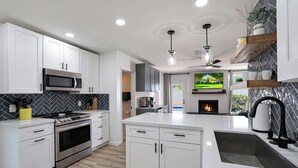A modern kitchen with white cabinetry, a built-in microwave, a stove, and a large island with a sink. - PAPAGO PLACE - Spacious 5-bedroom house in South Scottsdale (Scottsdale)