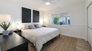 A bedroom with a bed, bedside tables, a ceiling fan, a window with blinds, and a potted plant. - PAPAGO PLACE - Spacious 5-bedroom house in South Scottsdale (Scottsdale)