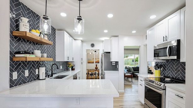 A modern kitchen with white cabinets, a central island, and a herringbone-patterned backsplash. - PAPAGO PLACE - Spacious 5-bedroom house in South Scottsdale (Scottsdale)