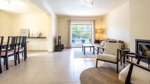 A spacious living room with a dining area, a sofa set, and a television.