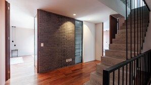 A modern interior with a wooden floor, a staircase with black railings, and a brick accent wall. - Queretaro 77 by Wynwood House (Mexico City)