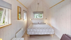 Ein Schlafzimmer mit einem Bett, zwei Fenstern, einem Spiegel und einer Heizung.
