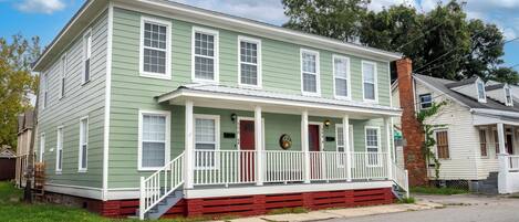 A two-story house with a front porch, a brick chimney, and a small front yard.
