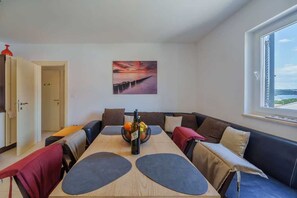 Ein modernes Wohnzimmer mit Esstisch, Sofas und einem großen Fenster.