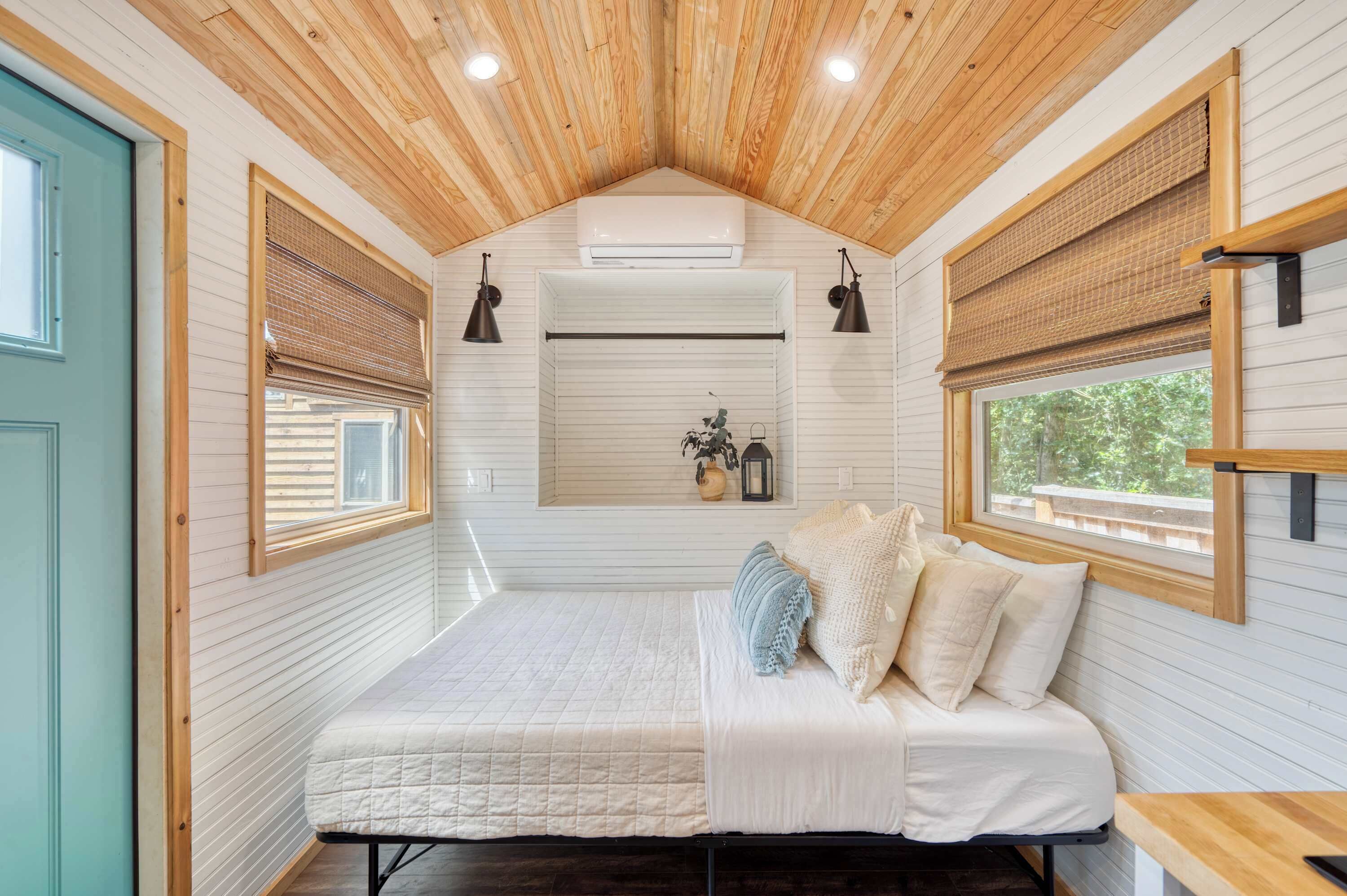 Een slaapkamer met een bed, houten plafond en ramen met zonwering.