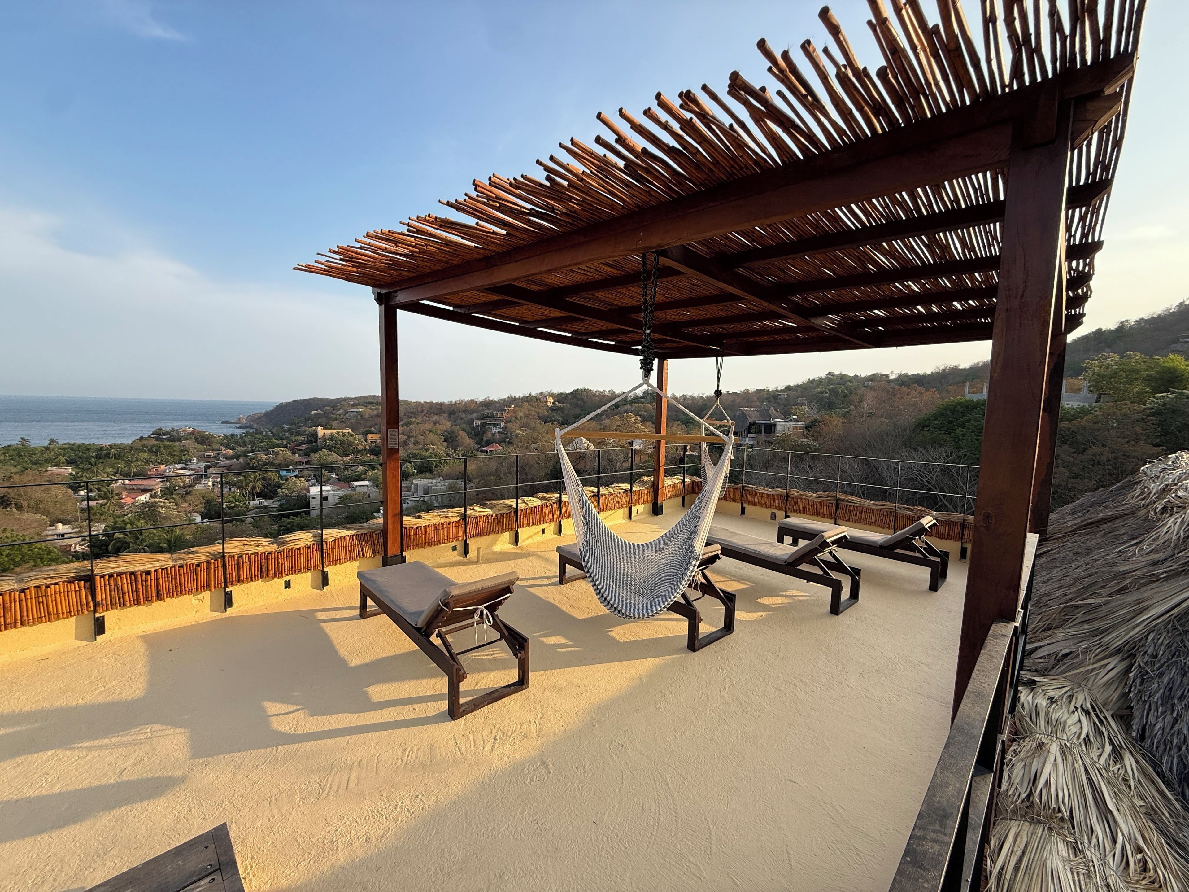 Une terrasse sur le toit avec un hamac, des chaises longues et une vue sur le paysage.