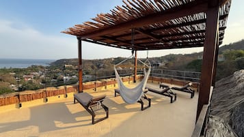 Une terrasse sur le toit avec un hamac, des chaises longues et une vue sur le paysage.