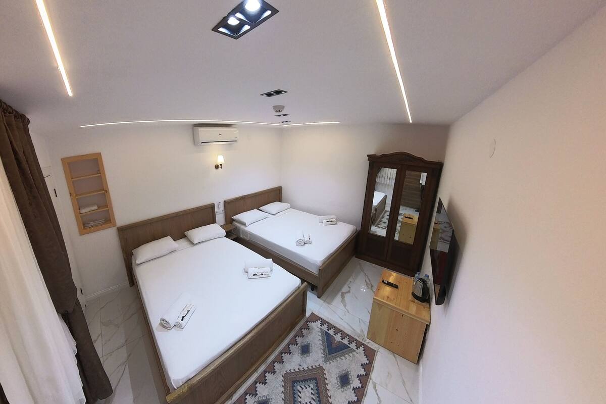 Habitación de hotel con dos camas, un armario, un espejo, un escritorio pequeño y un baño.