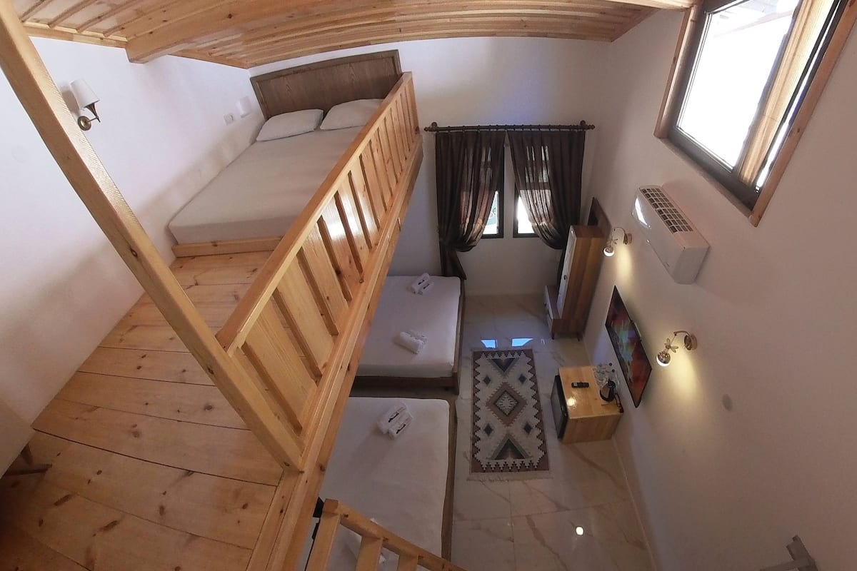 Habitación pequeña con una cama litera, un escritorio, una silla, un calentador y una ventana con cortinas.