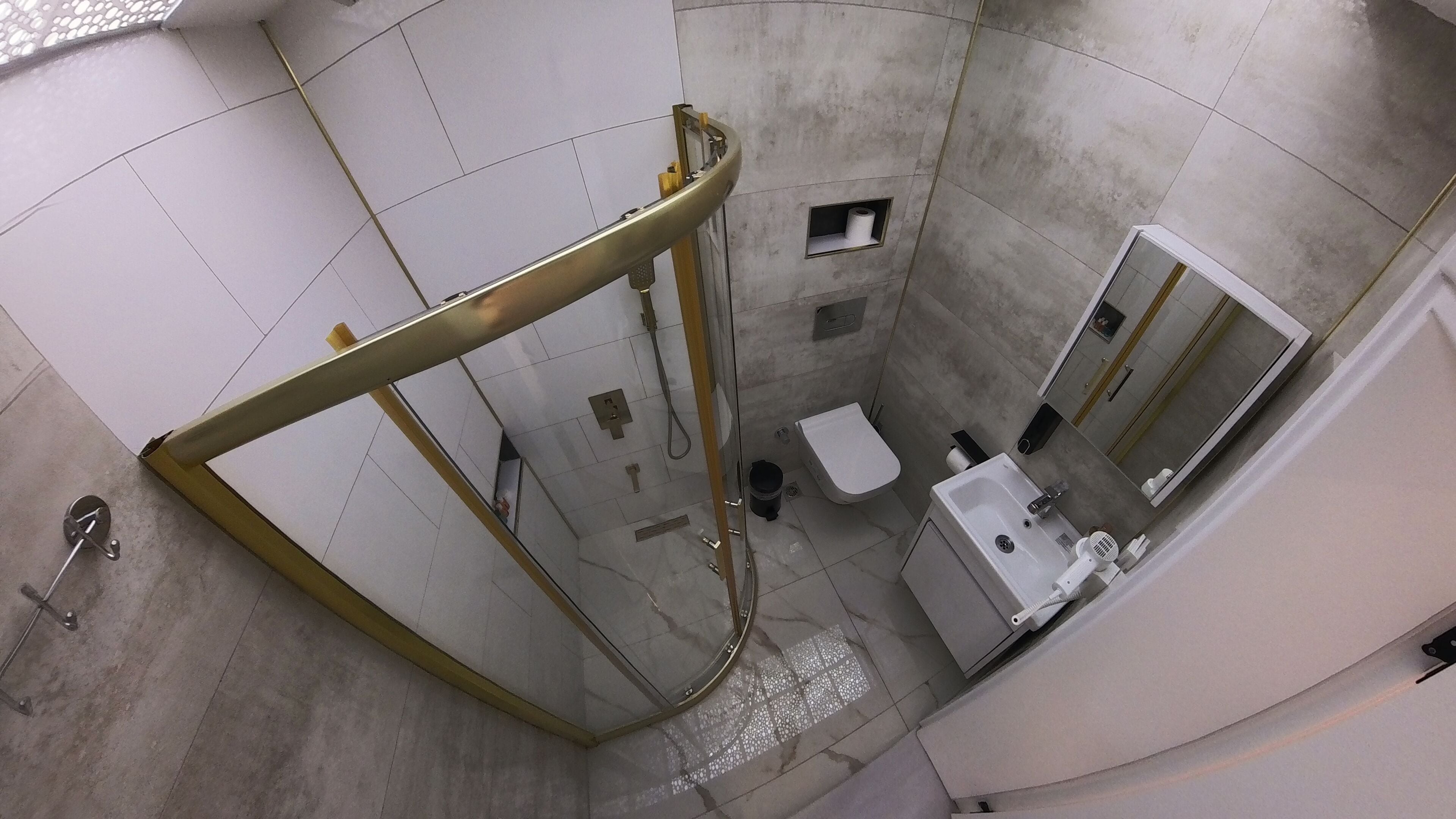 A modern bathroom with a glass-enclosed shower, a toilet, a sink, and a mirror.