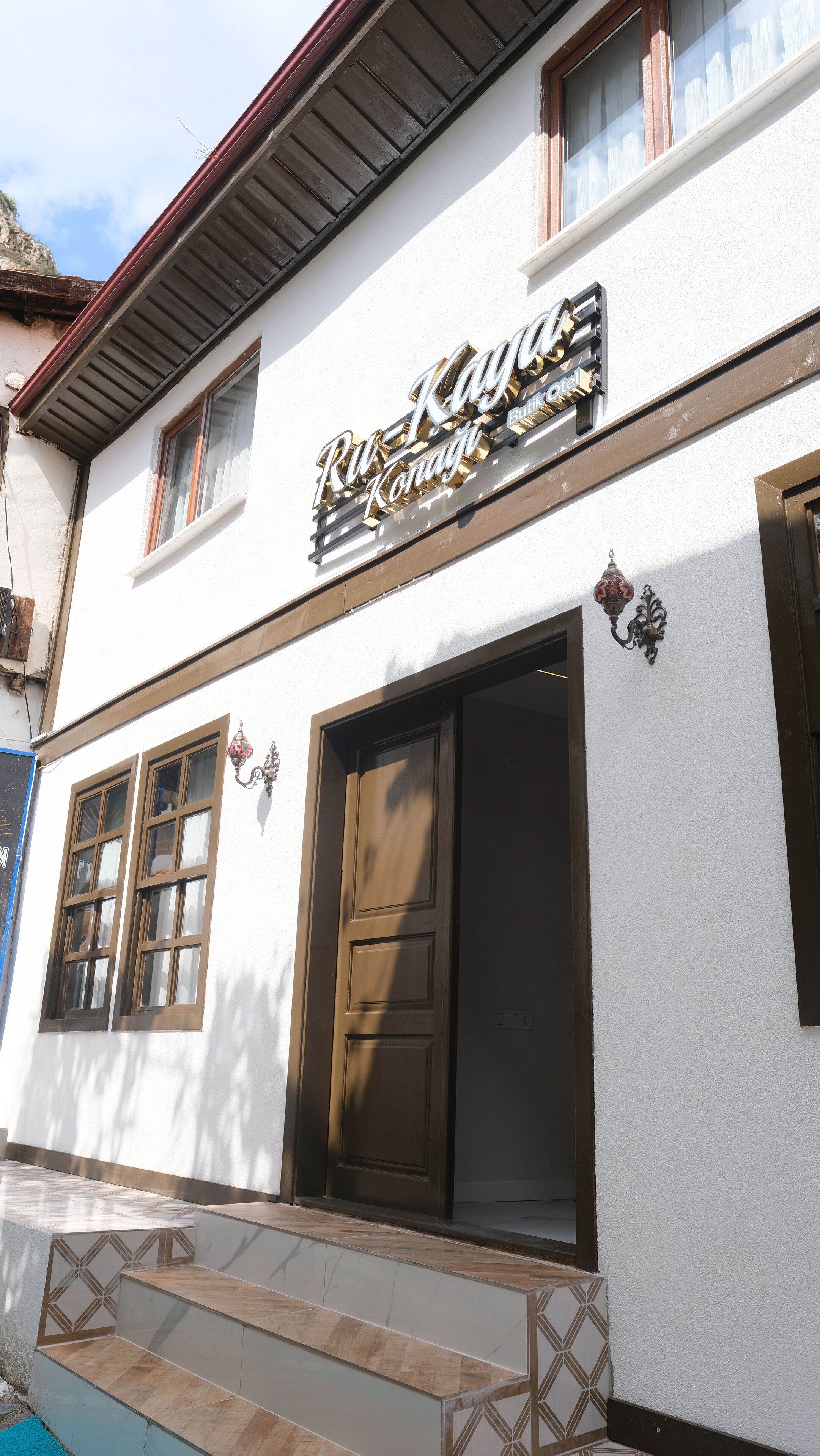 A hotel named "Ru-Kaya" with a white facade, large wooden doors, and a visible pool area.
