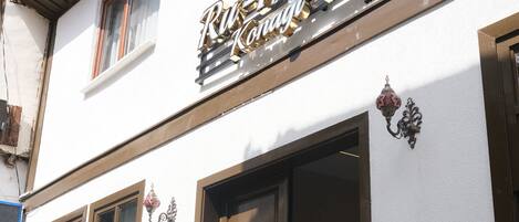 A hotel named "Ru-Kaya" with a white facade, large wooden doors, and a visible pool area.