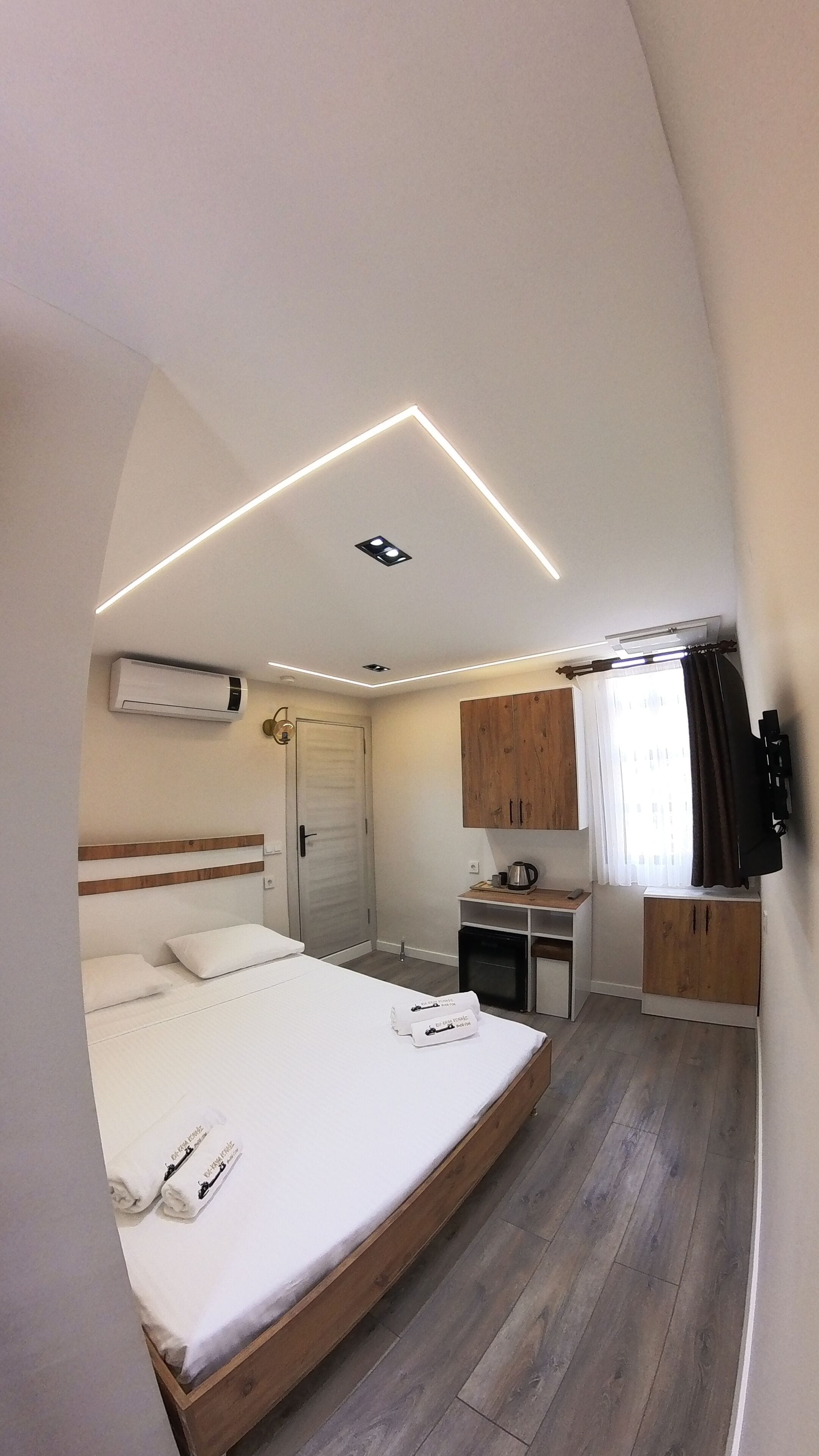 Une chambre moderne avec un lit, une table de chevet et une petite kitchenette.