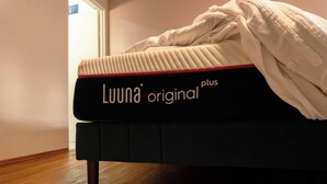 Una cama con colchón blanco, etiquetado como "Luna original plus", sobre un marco negro.