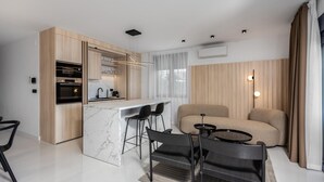 Een moderne keuken met een marmeren aanrecht, een ingebouwde oven en een eethoek met een bank en stoelen.