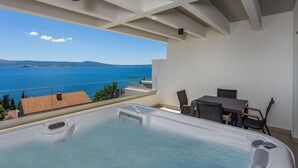 Een bubbelbad op een balkon met uitzicht op zee.