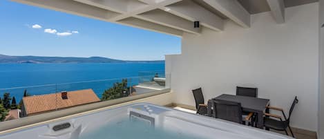 A hot tub on a balcony with a view of the sea.