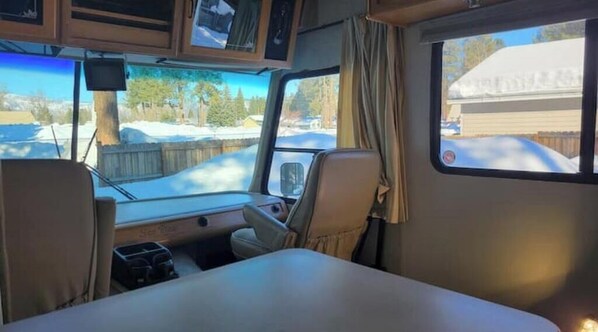 Enjoy the serene view from the central table in this cozy RV, where you can relax and take in the surrounding landscape.