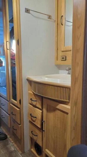 Features a sink and mirror above a spacious countertop with multiple drawers.