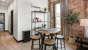 A modern kitchen with a round wooden table, bar stools, a metal shelving unit with kitchenware, and a brick wall. - Cozy 1-bedroom apartment in fabulous Wabash with WiFi, AC (Wabash)