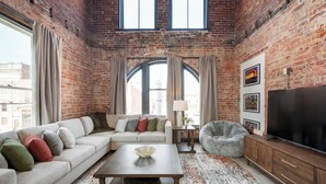 A living room with a brick wall, a sofa, a coffee table, a TV, and a lamp. - Cozy 1-bedroom apartment in fabulous Wabash with WiFi, AC (Wabash)