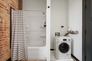 A modern bathroom with a shower, a bathtub, and a front-loading washing machine. - Cozy 1-bedroom apartment in fabulous Wabash with WiFi, AC (Wabash)