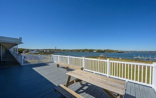 A wooden deck with white railings overlooking a body of water.