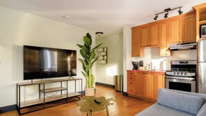 A modern kitchen with wooden cabinets, stainless steel appliances, and a flat-screen TV.