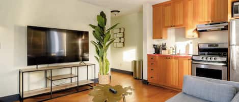 A modern kitchen with wooden cabinets, stainless steel appliances, and a flat-screen TV.