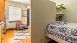 A compact room with a bed, a small seating area, and a kitchenette. - Perfect Hawthorne Micro By Top Shopping & Dining (Portland)
