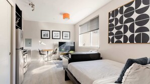 Una habitación de hotel moderna con cama, escritorio, silla y televisor.